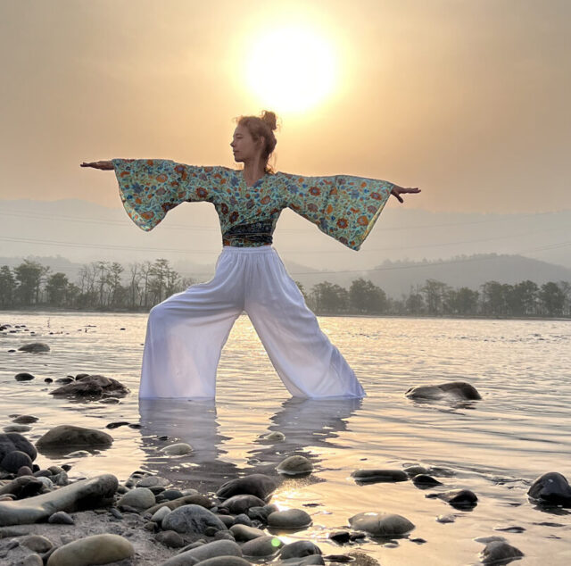 student practicing yoga pose at ganga with sunrise view